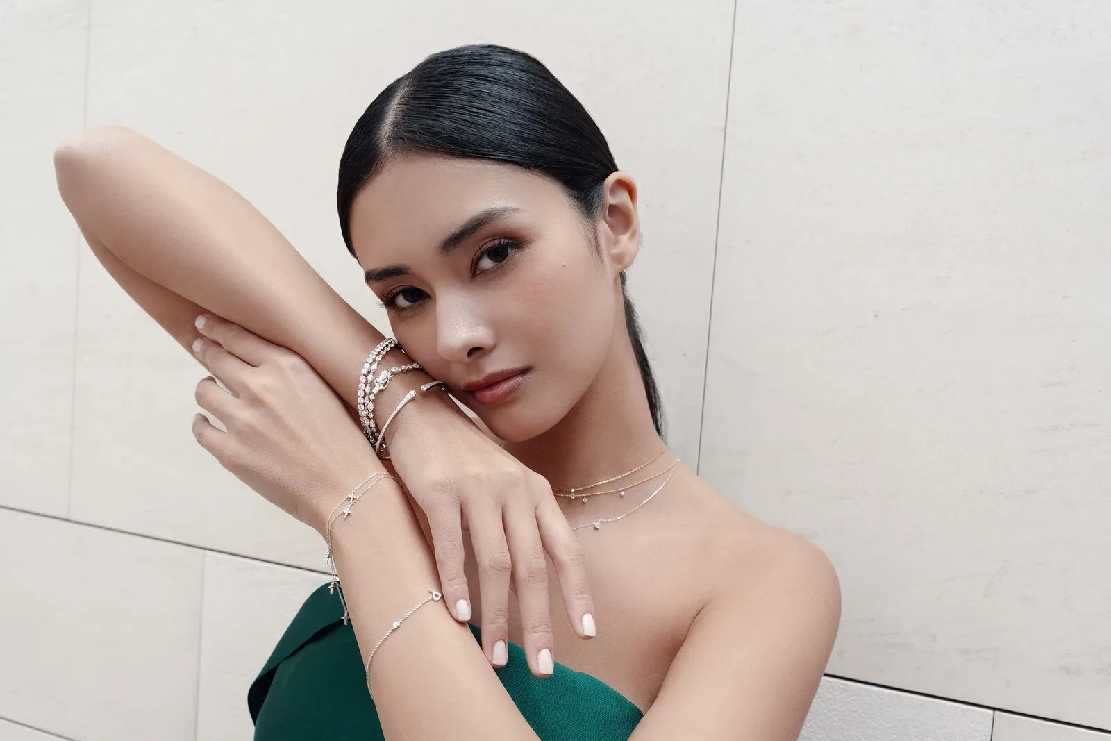 Diamanten tennisarmbanden, bangles en gelaagde kettingen over de arm gedragen