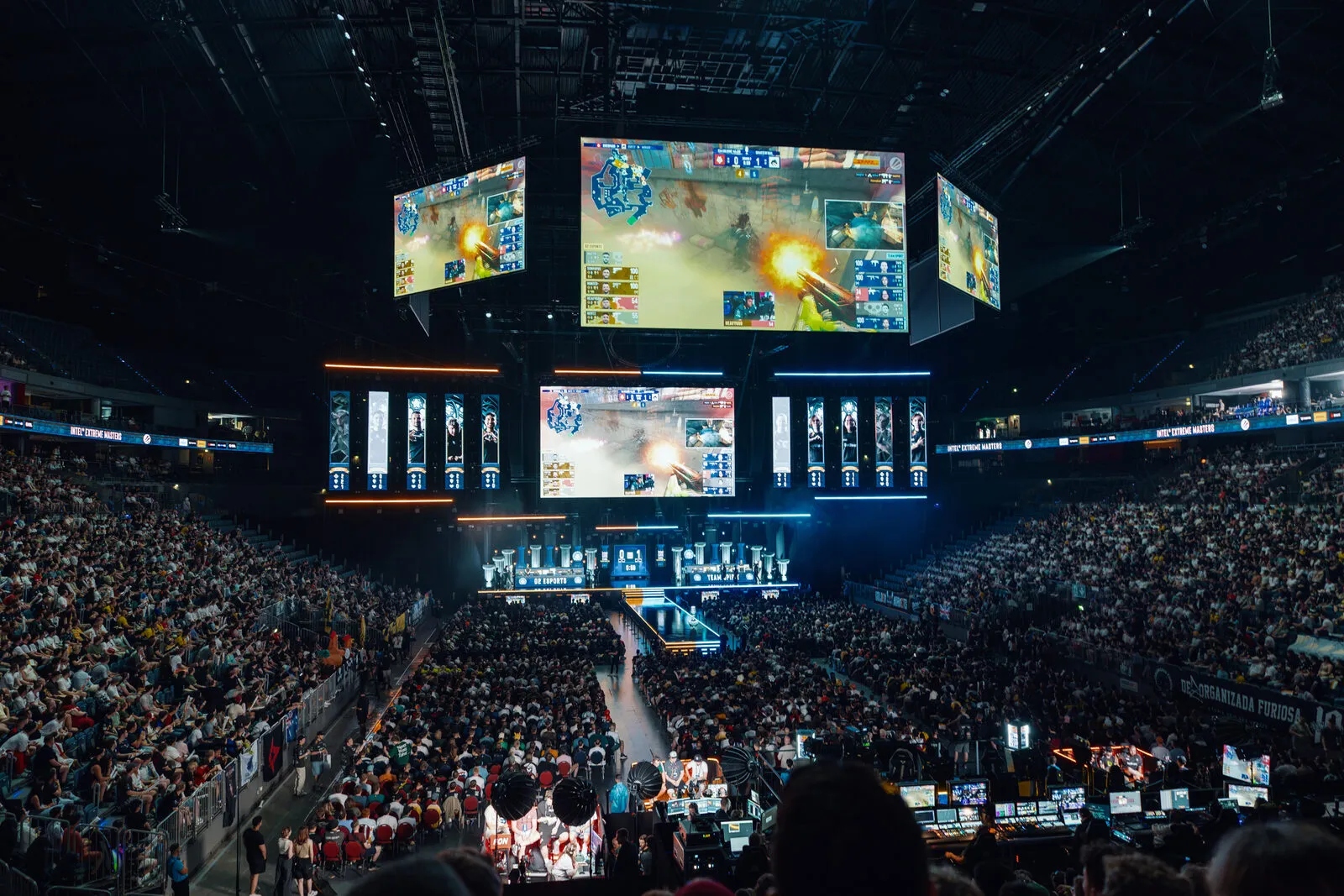 De arena vanaf de tribune: twee volle ringen, het podium blauw uitgelicht, de game op de schermen erboven