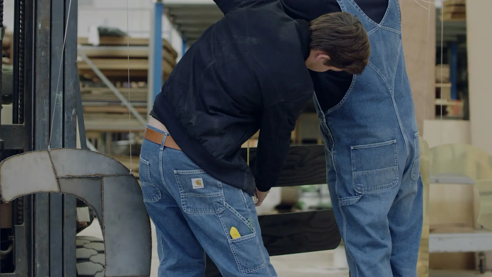 Een werker in Carhartt-jeans laadt hout op de heftruck