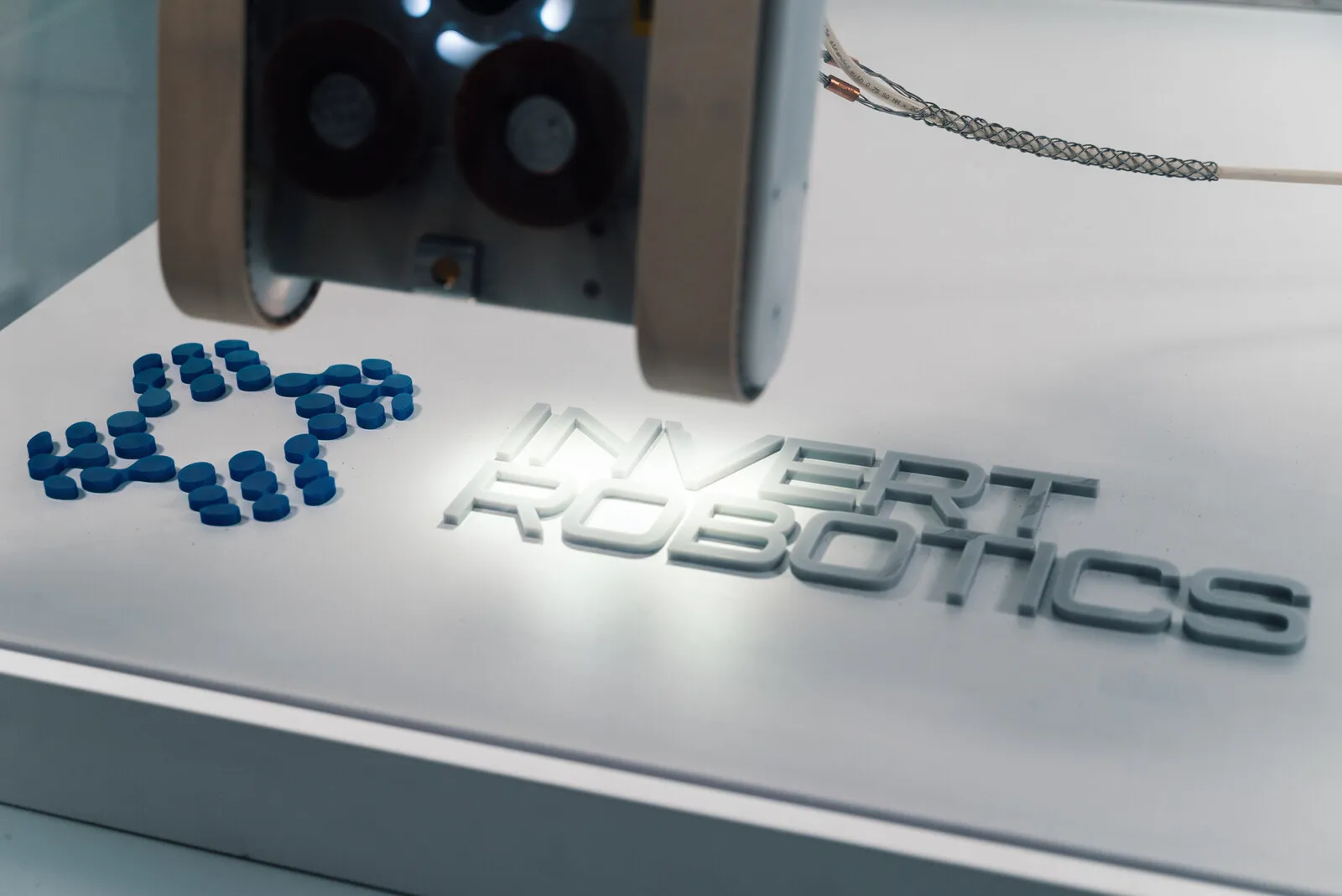 Het merkteken van Invert Robotics in reliëf op de witte behuizing