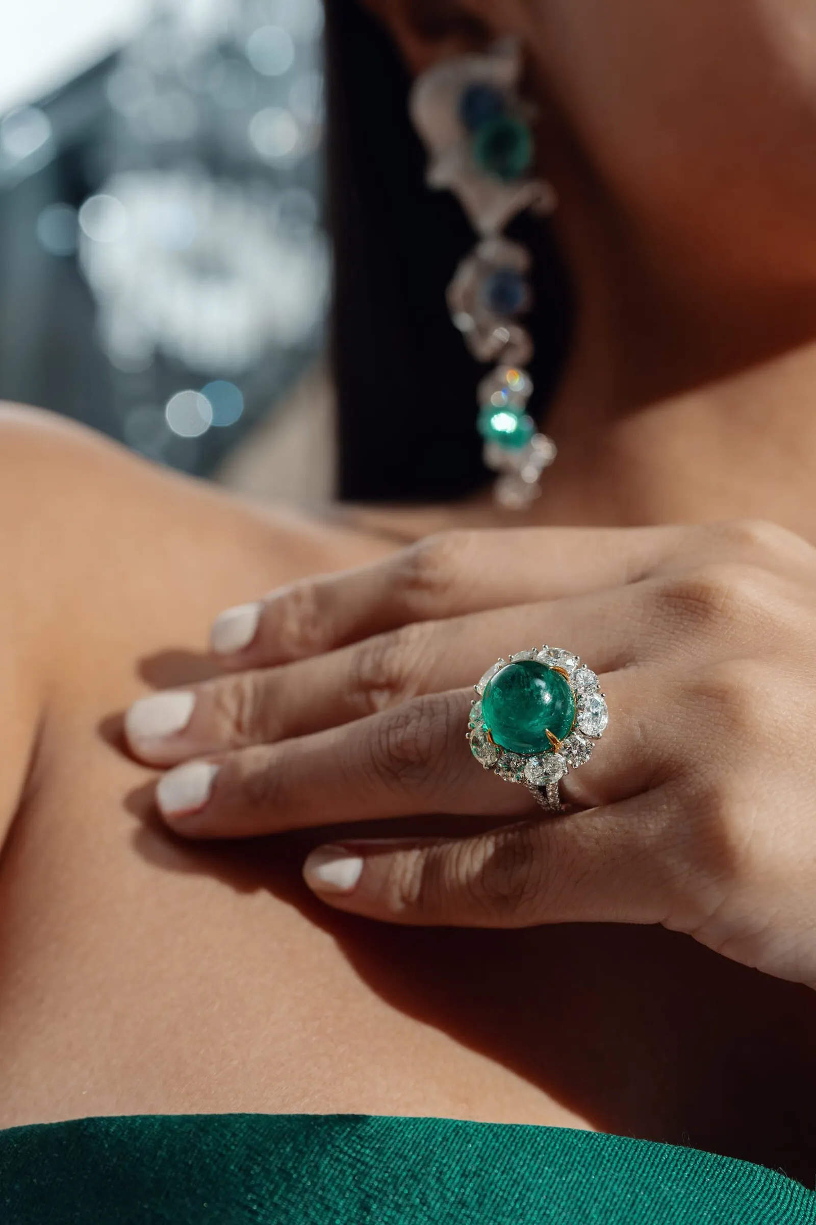 Ring met cabochon smaragd en bijpassende oorhanger, dichtbij op de hand