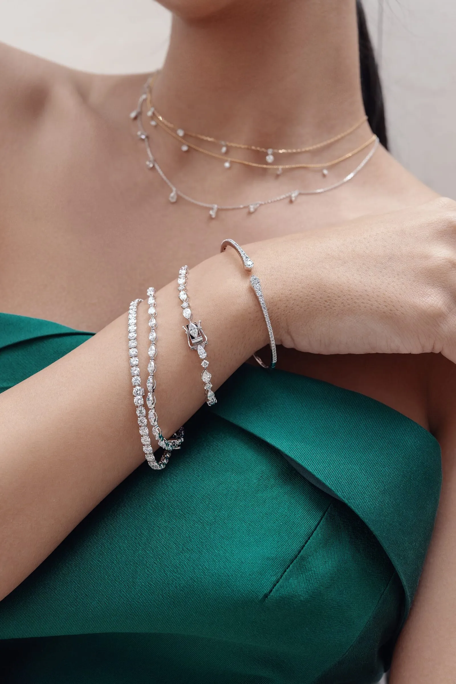 Drie diamanten armbanden en twee gelaagde diamanten chokers samen gedragen