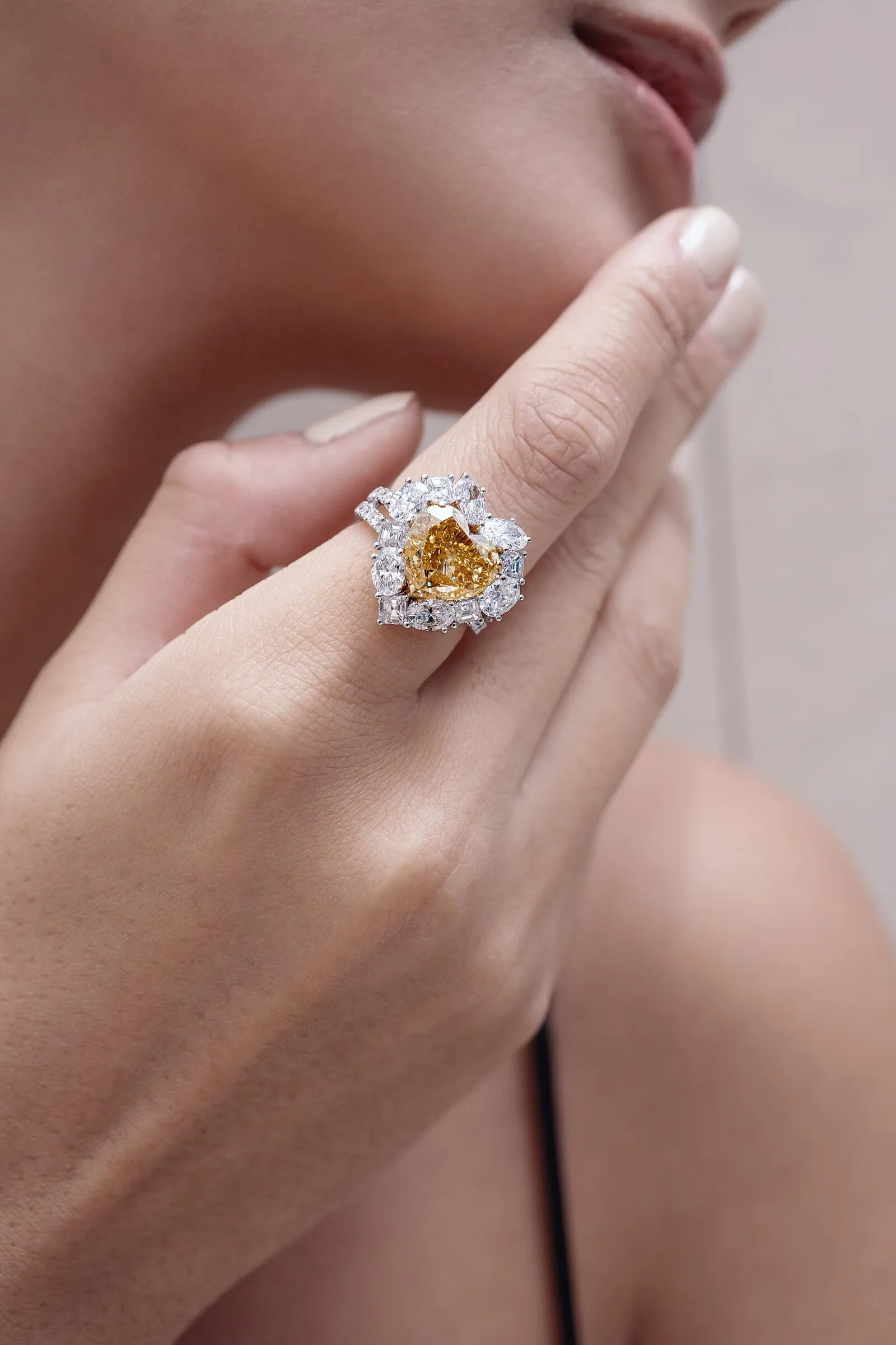 Ring met hartgeslepen fancy gele diamant in een cluster van witte peer- en smaragdslijpsels