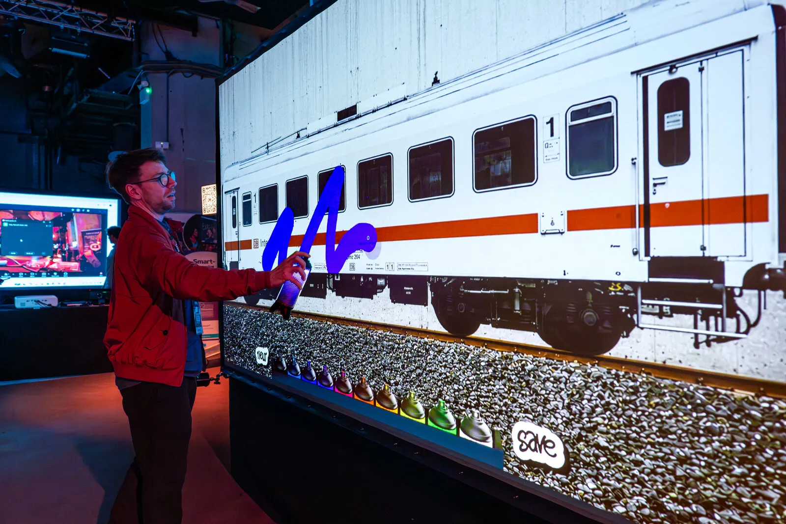 Een gast beschildert een geprojecteerde treinwagon met een lichtspuitbus