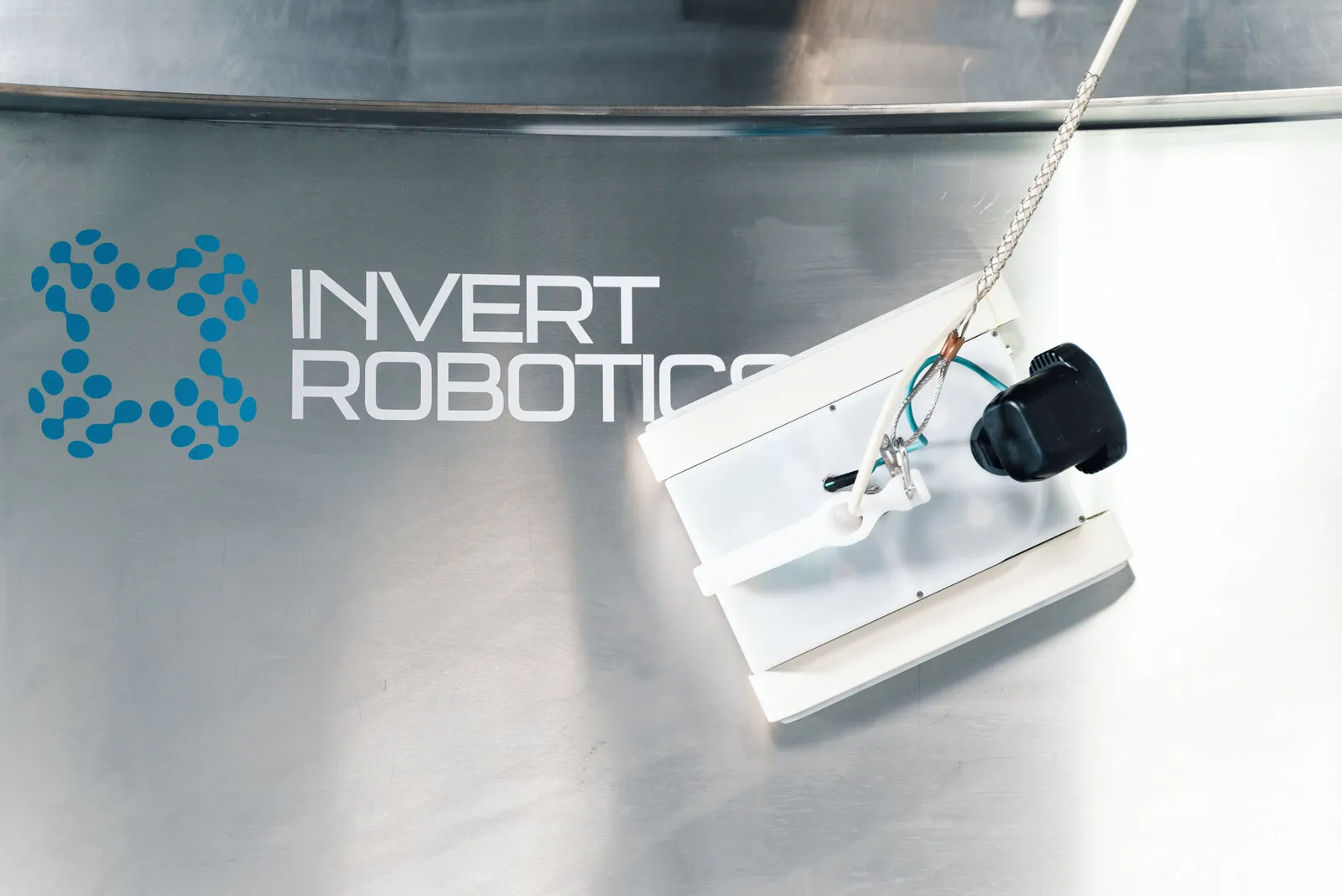 De crawler op een stalen oppervlak naast het merkteken van Invert Robotics