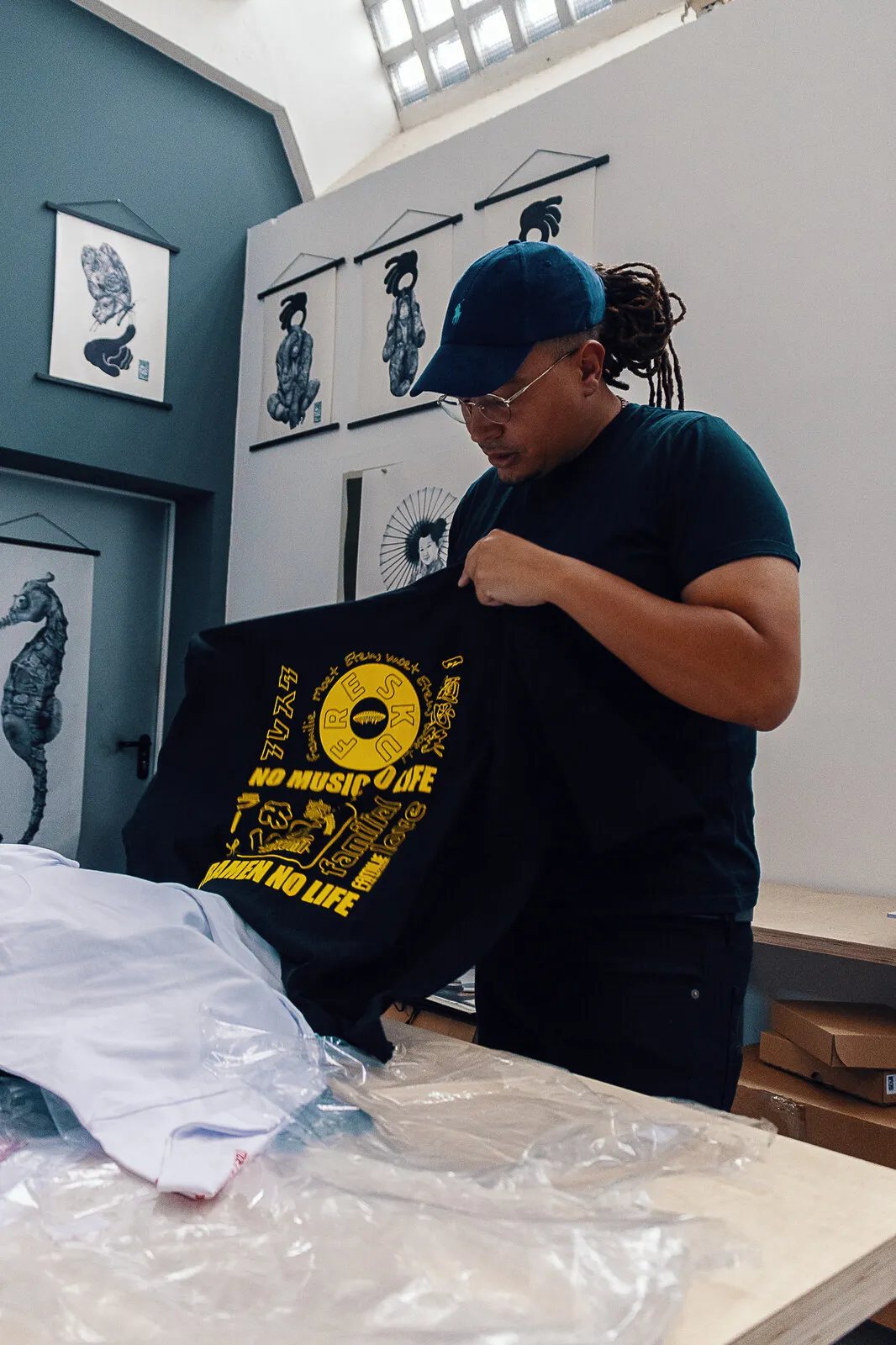Fresku houdt het zwarte shirt omhoog, met de gele print no music no life erover