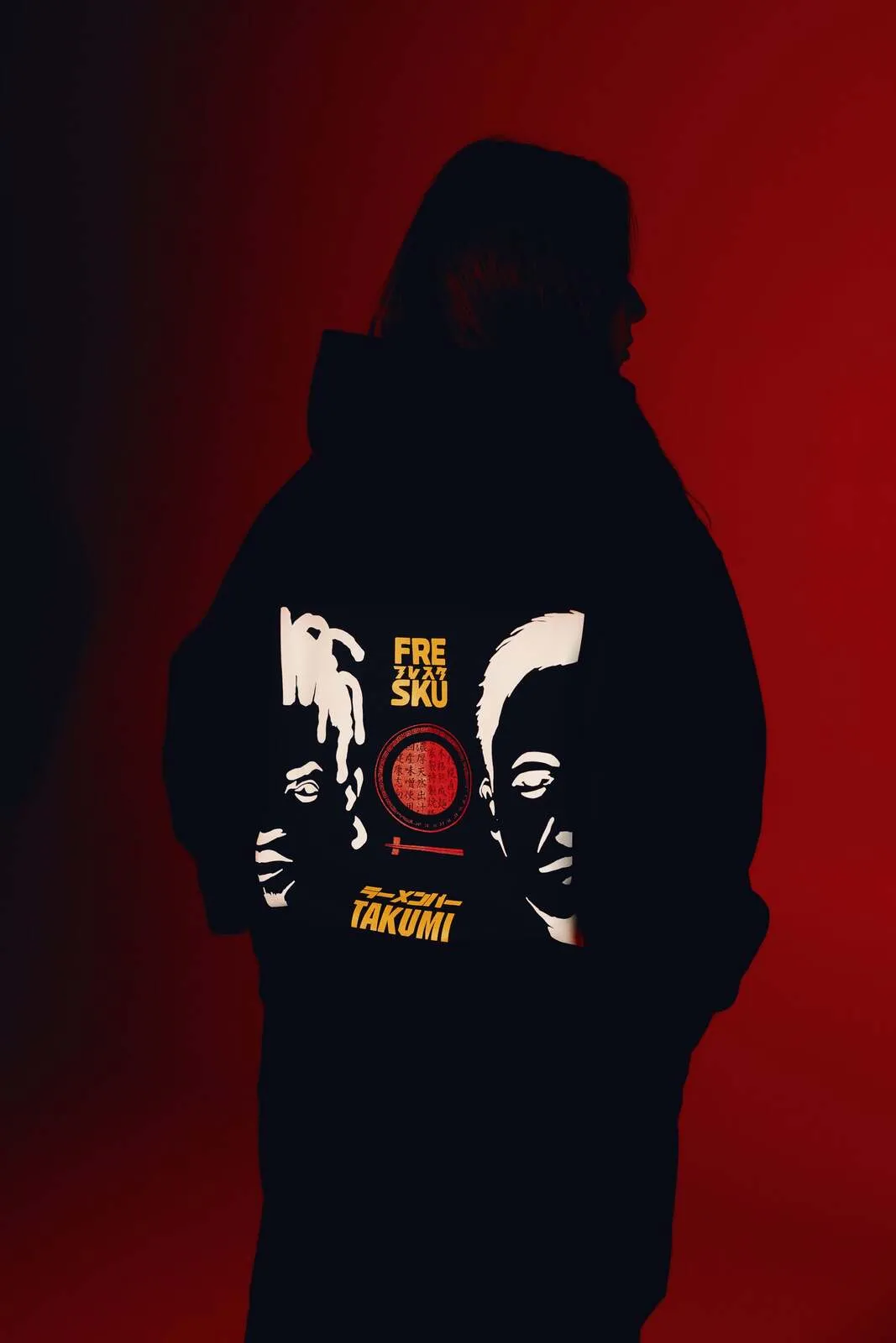De zwarte Fresku x Takumi hoodie, met het gezichtenwerk van Ogata over de rug