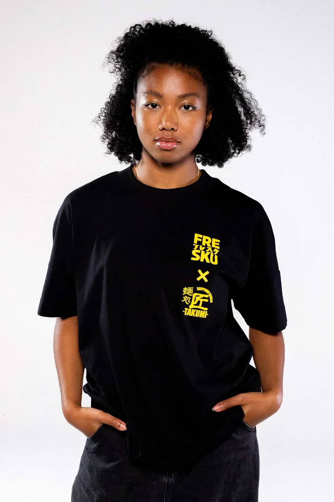 Het zwarte Fresku x Takumi shirt, met de borstlockup in geel uitgelicht
