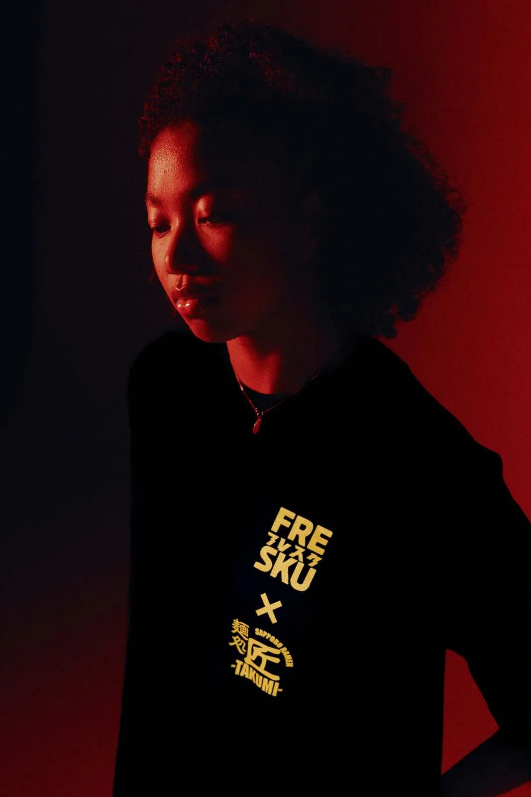 Het zwarte Fresku x Takumi shirt, met de borstlockup in geel uitgelicht