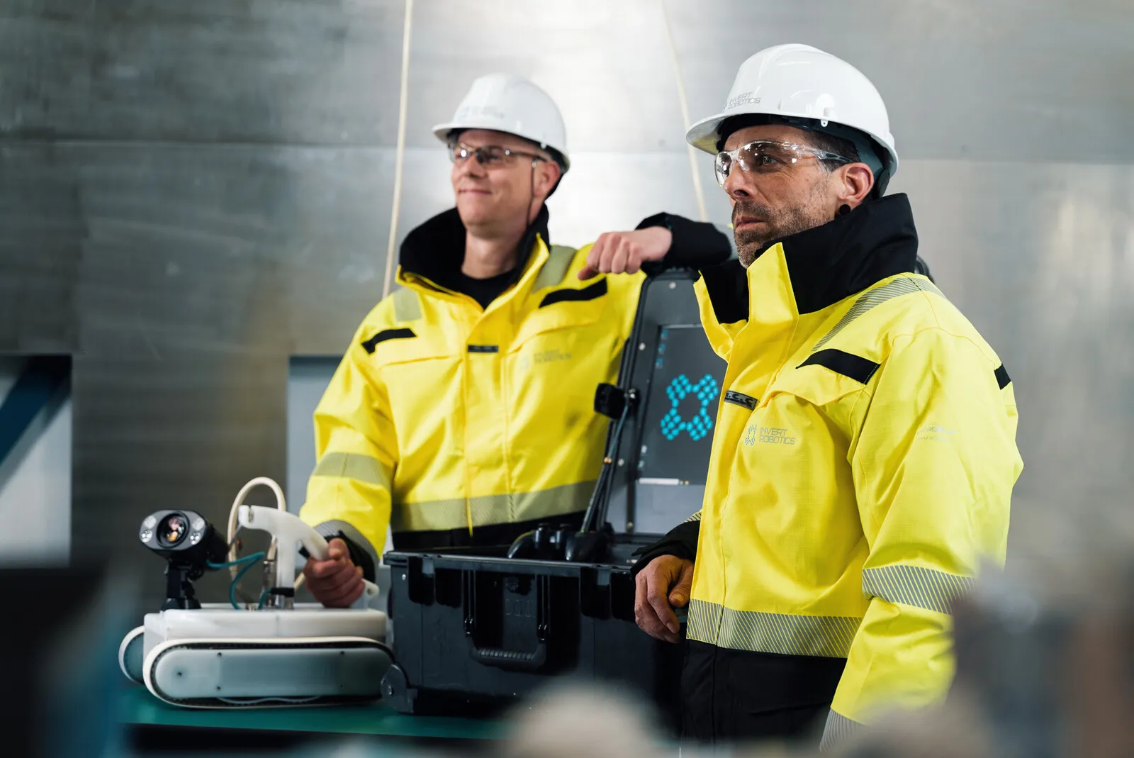 Twee operators in hesje en helm bij de bedieningskoffer